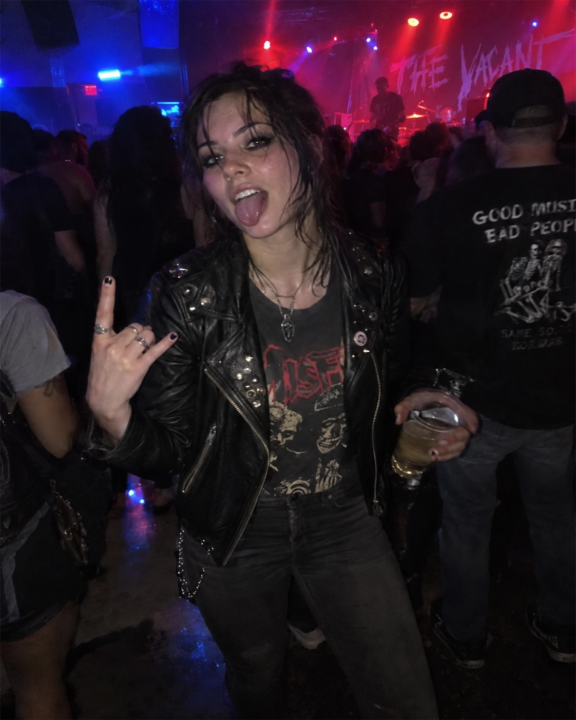 Person in a studded leather jacket over a band tee and skinny jeans